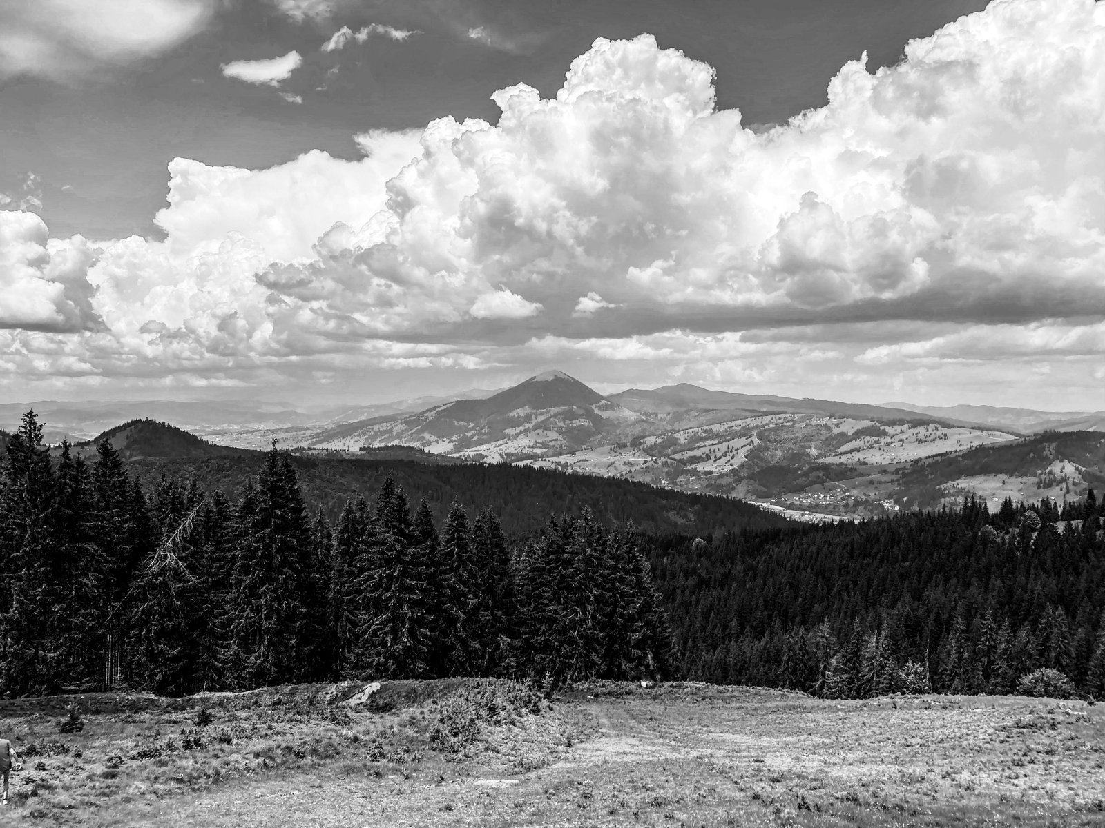 Black and white mountain clouds above a forest ridge