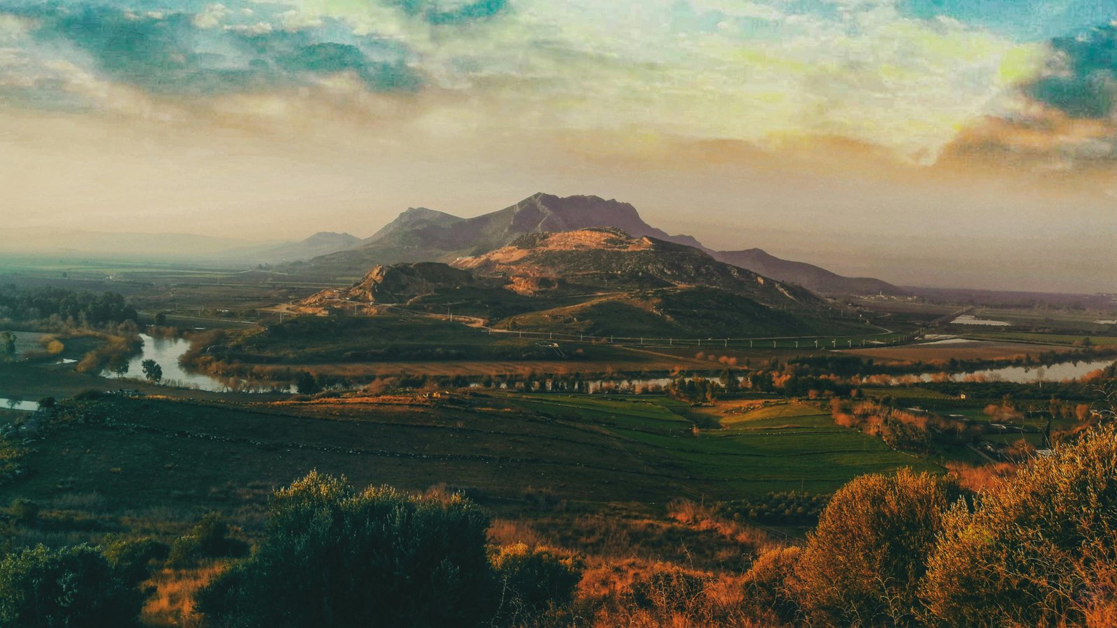 Warm valley and distant mountain under painterly clouds